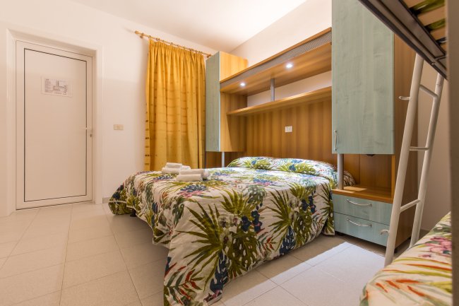 Camera da letto con letto matrimoniale e copriletto tropicale.