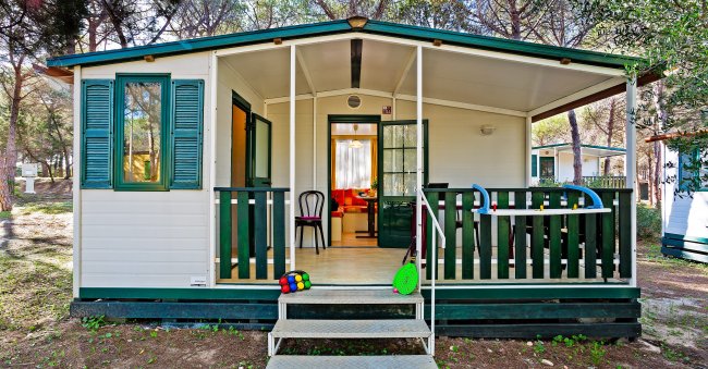 Casa mobile con veranda e giocattoli fuori.