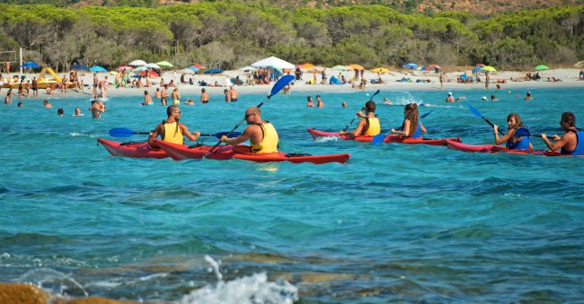 Persone in kayak su acque azzurre vicino alla spiaggia.