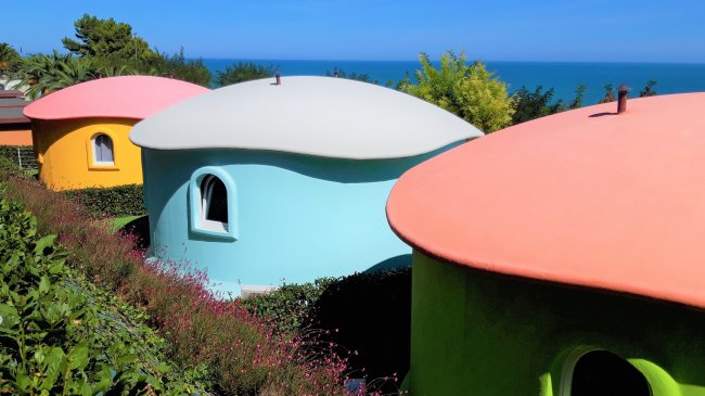 Case colorate a forma di fungo con vista sul mare.