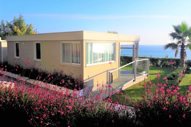 Casa moderna circondata da piante con vista sul mare.