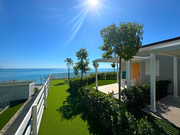 Giardino curato con vista mare, sole splendente e casa accogliente.