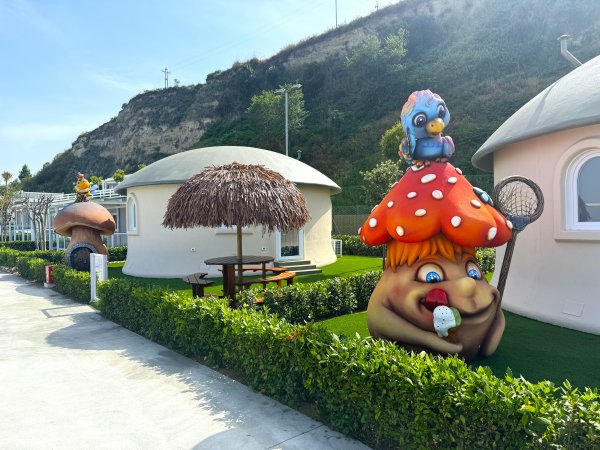 Sculture colorate a forma di funghi e case tondeggianti in giardino.