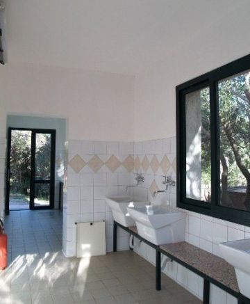 Un bagno con due lavandini bianchi e piastrelle quadrate, finestra grande a destra.
