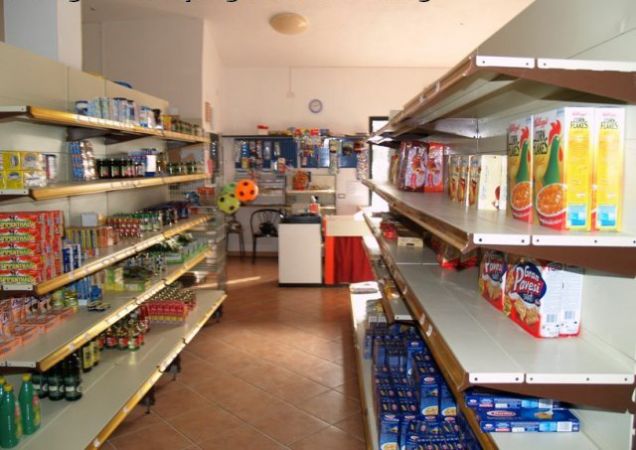 Corridoio di un alimentari con scaffali pieni di prodotti confezionati.